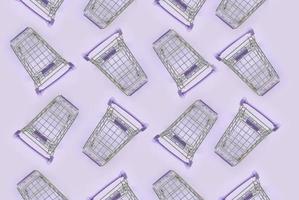 Pattern of many small shopping carts on a violet background. Minimalism flat lay top view photo