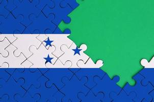 Honduras flag  is depicted on a completed jigsaw puzzle with free green copy space on the right side photo