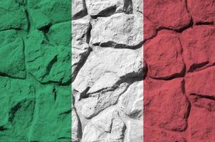 Italy flag depicted in paint colors on old stone wall closeup. Textured banner on rock wall background photo