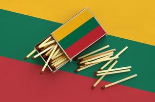 Lithuania flag  is shown on an open matchbox, from which several matches fall and lies on a large flag photo