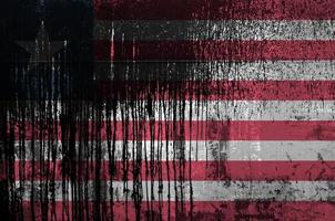 Liberia flag depicted in paint colors on old and dirty oil barrel wall closeup. Textured banner on rough background photo