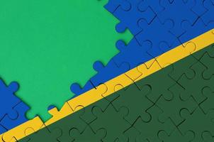 Solomon Islands flag  is depicted on a completed jigsaw puzzle with free green copy space on the left side photo