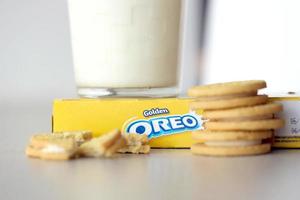 TERNOPIL, UKRAINE - MAY 28, 2022 Oreo golden crispy cookies with glass of milk on white background. The brand Oreo is owned by company Mondelez international photo