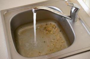 Stainless steel sink plug hole close up full of water and particles of food photo