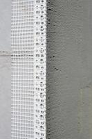 The texture of the wall, covered with gray polystyrene foam plates, which are coated with a reinforcing mixture with a plastic reinforcing profile corner. Stage of wall insulation photo