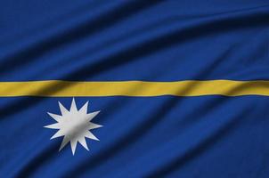 Nauru flag  is depicted on a sports cloth fabric with many folds. Sport team banner photo