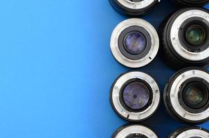 Several photographic lenses lie on a bright blue background. Space for text photo