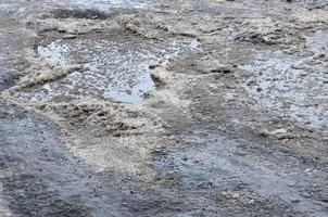 Damaged asphalt road with potholes caused by freezing and thawing cycles during the winter. Poor road photo