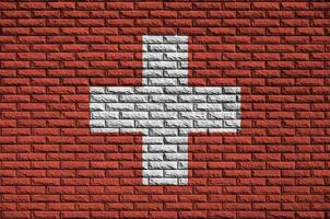 Switzerland flag is painted onto an old brick wall photo