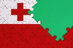 Tonga flag  is depicted on a completed jigsaw puzzle with free green copy space on the right side photo