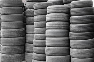 Old used tires stacked with high piles in secondary car parts shop garage photo