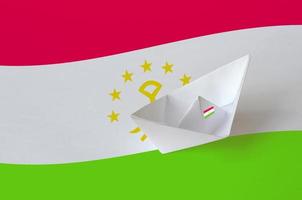 bandera de tayikistán representada en el primer barco de origami de papel. concepto de artes hechas a mano foto