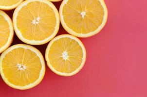 Top view of a several orange fruit slices on bright background in red color. A saturated citrus texture image photo