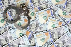 Silver police handcuffs lies on a many dollar bills photo