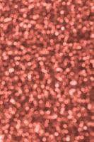 Blurred orange decorative sequins. Background image with shiny bokeh lights from small elements photo