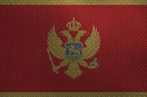 Montenegro flag depicted in paint colors on old brushed metal plate or wall closeup. Textured banner on rough background photo