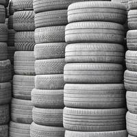 Old used tires stacked with high piles in secondary car parts shop garage photo