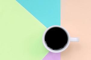 Small white coffee cup on texture background of fashion pastel pink, blue, coral and lime colors paper photo