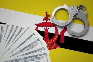 Brunei Darussalam flag  with handcuffs and a bundle of dollars. The concept of illegal banking operations in US currency photo