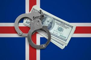 Iceland flag  with handcuffs and a bundle of dollars. Currency corruption in the country. Financial crimes photo