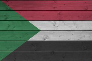 Sudan flag depicted in bright paint colors on old wooden wall. Textured banner on rough background photo