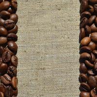 Texture of a gray canvas made of old and coarse burlap with coffee beans on it photo