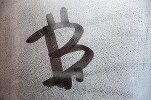 The bitcoin symbol on the misted sweaty glass. Abstract background image. Cryptocurrency concept photo