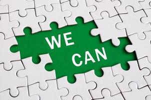 White jigsaw puzzle in assembled state with missing elements forming a green space with white inscription. We can photo