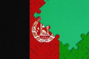 Afghanistan flag is depicted on a completed jigsaw puzzle with free green copy space on the right side photo