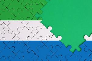 Sierra Leone flag  is depicted on a completed jigsaw puzzle with free green copy space on the right side photo