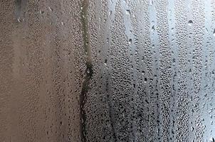 Texture of a drop of rain on a glass wet transparent background. Toned in grey color photo