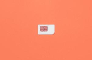 Subscriber identity module. White SIM card on coral red background photo