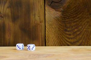 A few dice lies on the surface of natural wood. Items for generating numbers from one to six in the form of points that are painted on the side of cubes. The concept of gambling photo