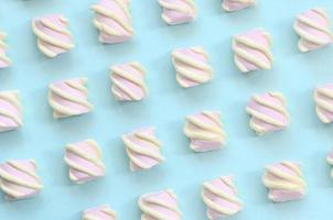 Colorful marshmallow laid out on blue paper background. pastel creative textured pattern. minimal photo