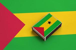 Sao Tome and Principe flag  is pictured on a matchbox that lies on a large flag photo