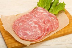 Sliced sausage on wooden board and wooden background photo