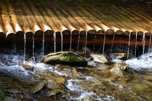 Handmade wooden water drains from small treated beams. A beautiful fragment of a small waterfall photo
