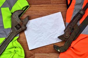 Adjustable wrenches and paper lies of an orange and green signal worker shirts photo