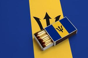 Barbados flag  is shown in an open matchbox, which is filled with matches and lies on a large flag photo