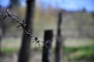 Macro shot of an element of old and rusty barbed wire with a blurred background. Fragment of a village fence of a territorial site photo