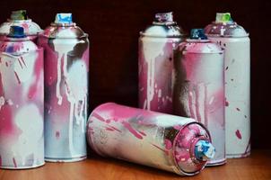 Still life with a large number of used colorful spray cans of aerosol paint lying on the treated wooden surface in the artist's graffiti workshop. Dirty and stained cans for spray art photo