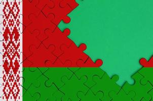 Belarus flag  is depicted on a completed jigsaw puzzle with free green copy space on the right side photo