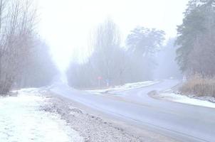 Crossroads on a suburban asphalt road in wintertime during a blizzard photo