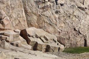 Light coarse natural rock stone background. Mining cliff rough front surface. Big limestone stack backdrop. Heavy grunge damaged granite block texture photo