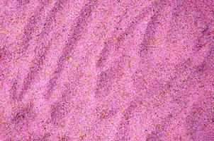 Texture of a colored granular sand close up. Pink grains photo