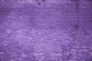 The texture of the brick wall of many rows of bricks painted in violet color photo