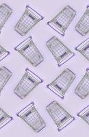 Pattern of many small shopping carts on a violet background. Minimalism flat lay top view photo