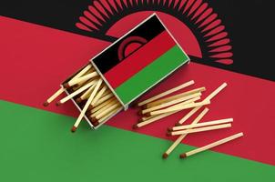 Malawi flag  is shown on an open matchbox, from which several matches fall and lies on a large flag photo