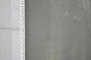 The texture of the wall, covered with gray polystyrene foam plates, which are coated with a reinforcing mixture with a plastic reinforcing profile corner. Stage of wall insulation photo