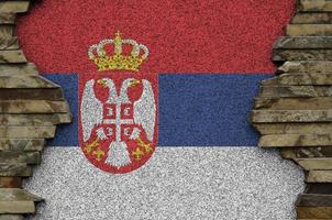 Serbia flag depicted in paint colors on old stone wall closeup. Textured banner on rock wall background photo